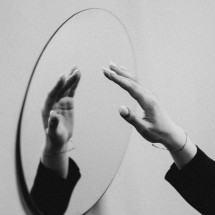 A hand touching a round mirror